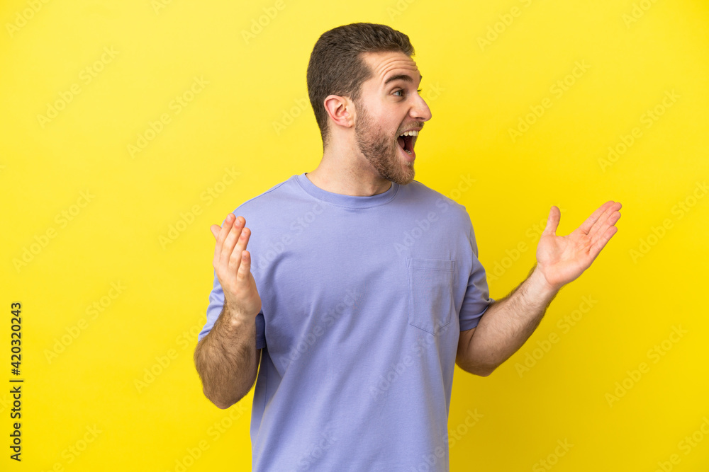 Handsome blonde man over isolated yellow background with surprise facial expression Handsome blonde man over isolated yellow background with surprise facial expression