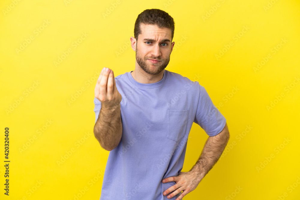 Handsome blonde man over isolated yellow background making Italian gesture Handsome blonde man over isolated yellow background making Italian gesture