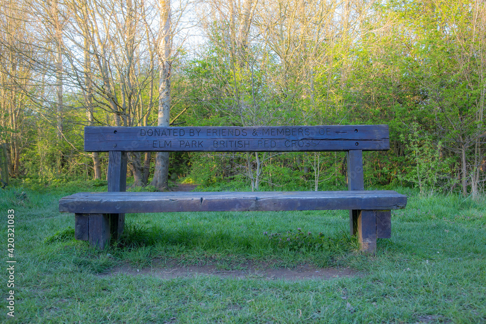 Old rustic wooden bench in elm park with the message donated by friends and members of elm park british red cross Old rustic wooden bench in elm park with the message donated by friends and members of elm park british red cross