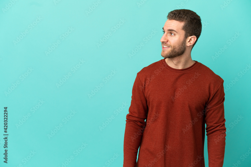 Handsome blonde man over isolated blue background looking to the side and smiling Handsome blonde man over isolated blue background looking to the side and smiling