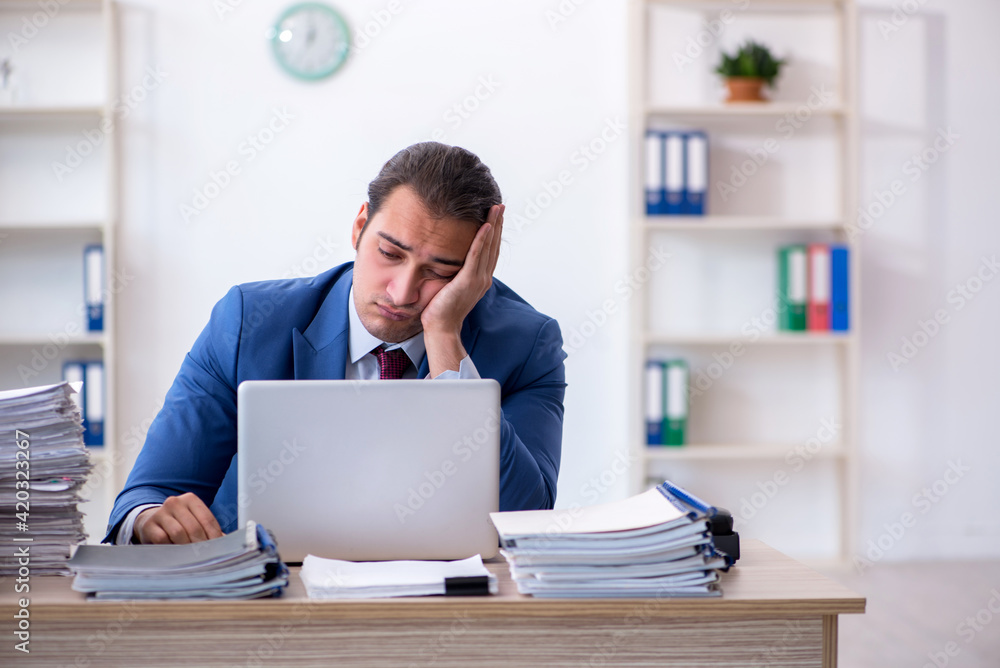 Young male employee unhappy with excessive work in the office Young male employee unhappy with excessive work in the office
