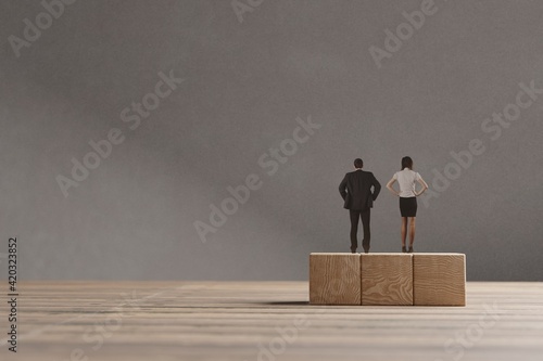 Miniature man and woman standing on the wooden blocks. The concept of equal opportunities for genders.