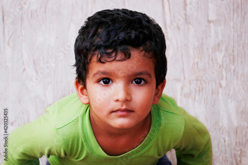 three year old indian baby boy in close up looking with green t shirt