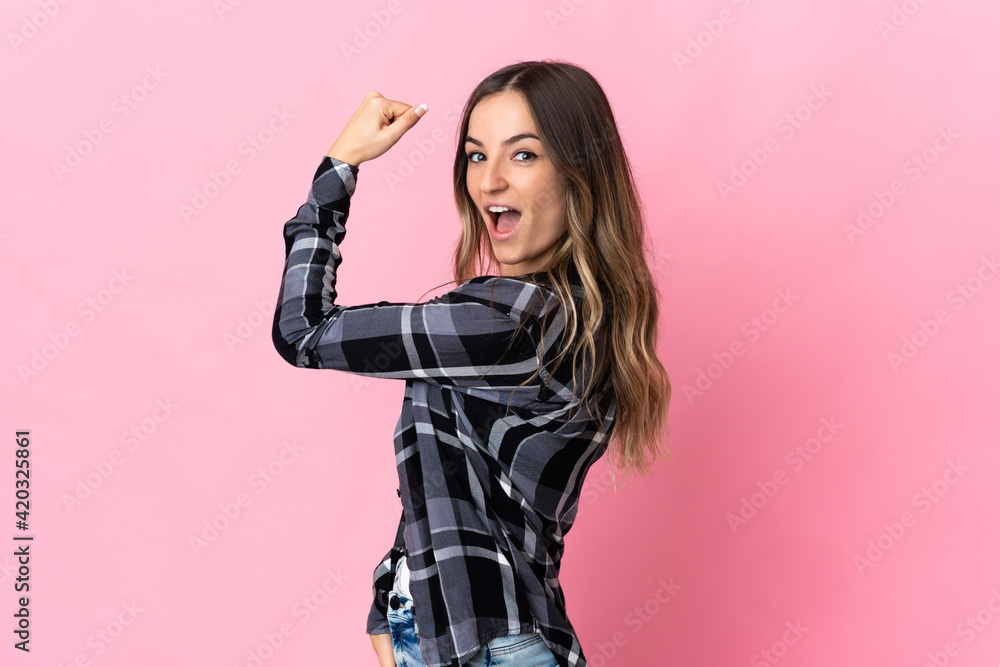 Young Romanian woman isolated on pink background doing strong gesture Young Romanian woman isolated on pink background doing strong gesture