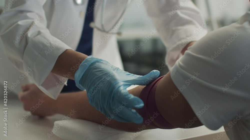 Without a face, a laboratory assistant in the clinic puts a tourniquet on the patients arm and takes a syringe in his hand for an intravenous injection Without a face, a laboratory assistant in the clinic puts a tourniquet on the patients arm and takes a syringe in his hand for an intravenous injection