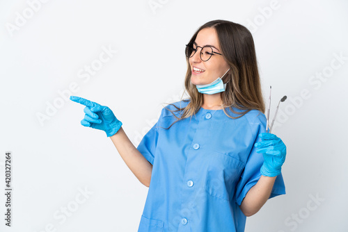 Woman Romanian dentist holding tools over isolated on pink background pointing finger to the side and presenting a product