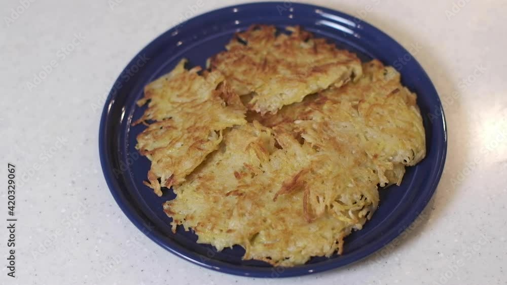 Fried potato pancakes are put on a plate. Video recipe.