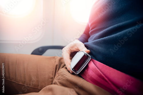 Fotografie Man passenger fastening seat while belt sitting on airplane
