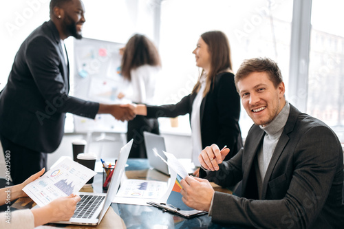 Wallpaper Mural Happy businessman in formal suit is sitting in office at the conference, learning financial graphs. Young adult male manager is looking directly at the camera and smile Torontodigital.ca