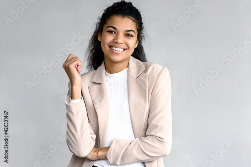 Portrait of elegant happy business woman or student in stylish formal suit. Beautiful young female is standing on isolated background, looking directly at the camera, smiling