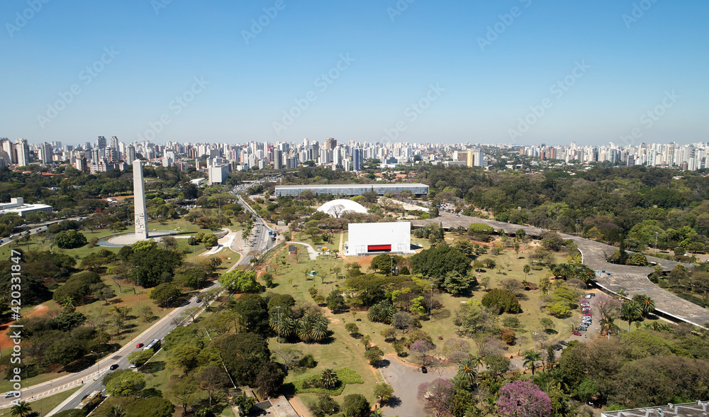 Aerial view of Ibirapuera park in Sao Paulo city. Prevervetion area with trees and green area of Ibirapuera park. Office buildings and apartments in the background on a sunny day.