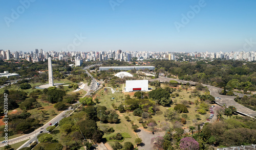 Aerial view of Ibirapuera park in Sao Paulo city. Prevervetion area with trees and green area of Ibirapuera park. Office buildings and apartments in the background on a sunny day.
