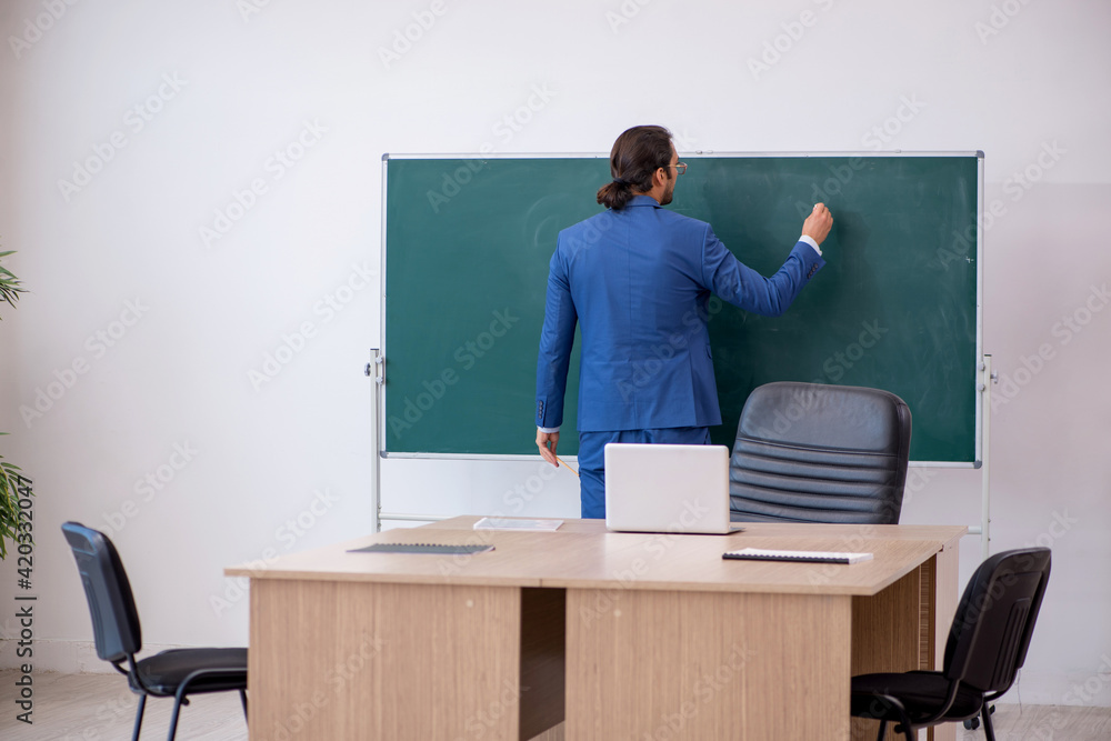 Young male teacher in suit in front of green board Young male teacher in suit in front of green board