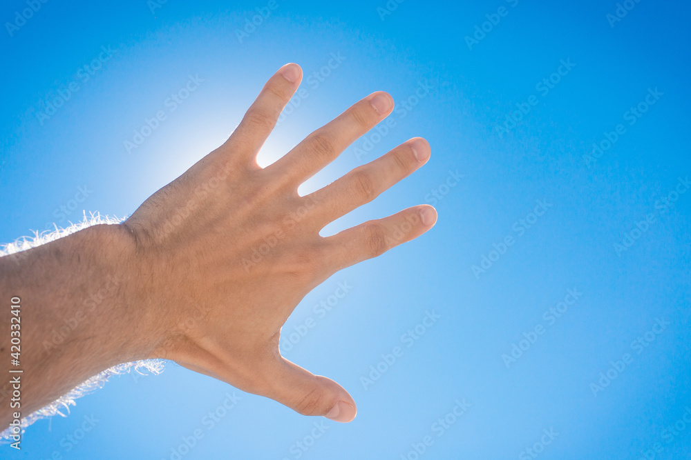 The guy stretched his hand forward towards the blue sky and the sun. The concept of freedom The guy stretched his hand forward towards the blue sky and the sun. The concept of freedom