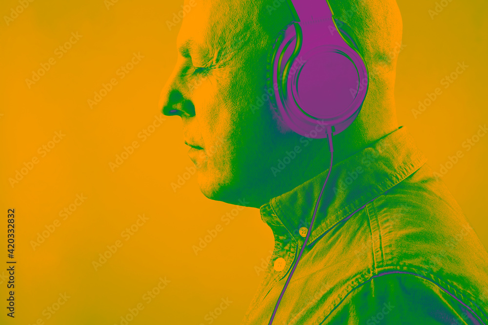 portrait of a man in acid bright color with headphones in relaxation listening to music