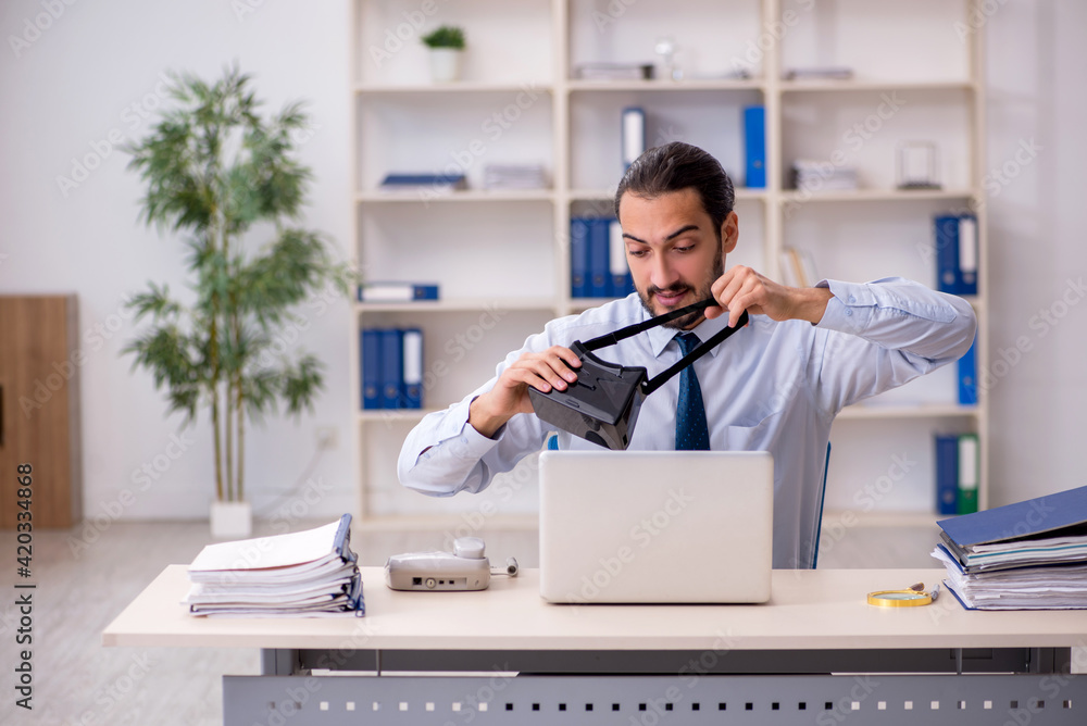 Young male employee wearing virtual glasses at workplace Young male employee wearing virtual glasses at workplace