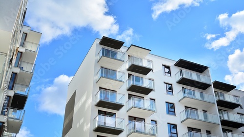 Futuristic square architecture of apartment building. Real estate with panoramic windows and blue sky with clouds.