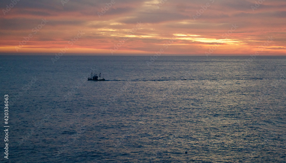 Fishing boat on the ocean in the sundown