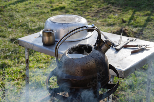 Water boils in a metal kettle in the garden. Cooking outdoors during tough times. Without gas and electricity. Rocket stove.