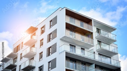 Futuristic square architecture of apartment building. Real estate with panoramic windows and blue sky with clouds.