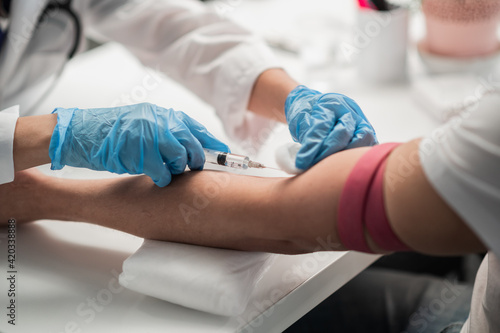 A nurse in the lab takes a blood test from a vein, a close-up plan without a face.
