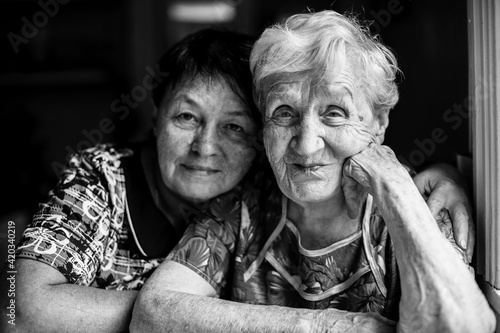 An old woman with her adult daughter. Black and white photo.