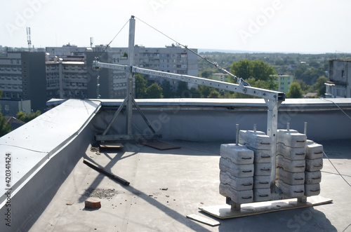 Counter weight or weight balance concrete blocks or bricks as part of suspended wire rope platform for facade works on high multistorey buildings. Many blocks with metal handles photo