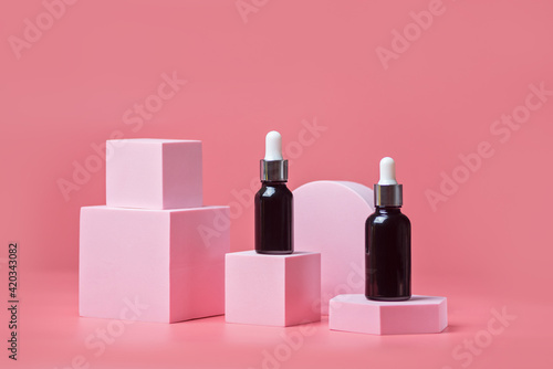 Serum in brown glass bottles with a pipette on a light pink background on pink podiums, mockup