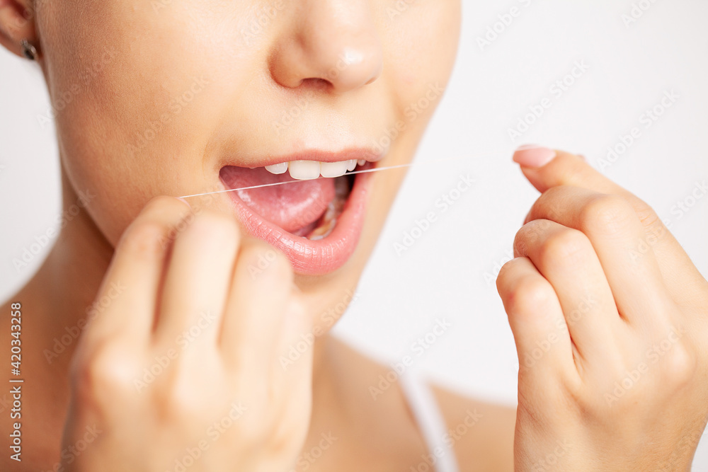 Obraz premium Cheerful brunette woman using dental floss in bathroom