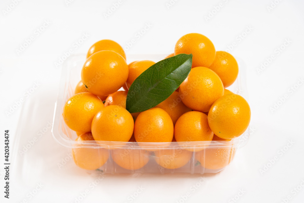 A box of kumquat with a green leaf isolated on white background, seasonal fruit