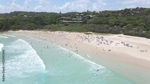 People Swim And Surf At Cylinder Beach - Campground Tents At Sandy Shore - Point Lookout, QLD, Australia. - aerial photo