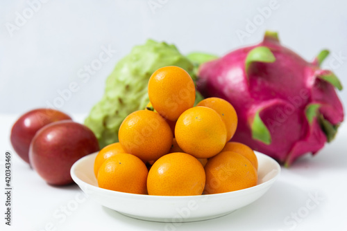 Multiple fruit combination platter isolated on white background, kumquat, red plums, dragon fruit and sugar apple