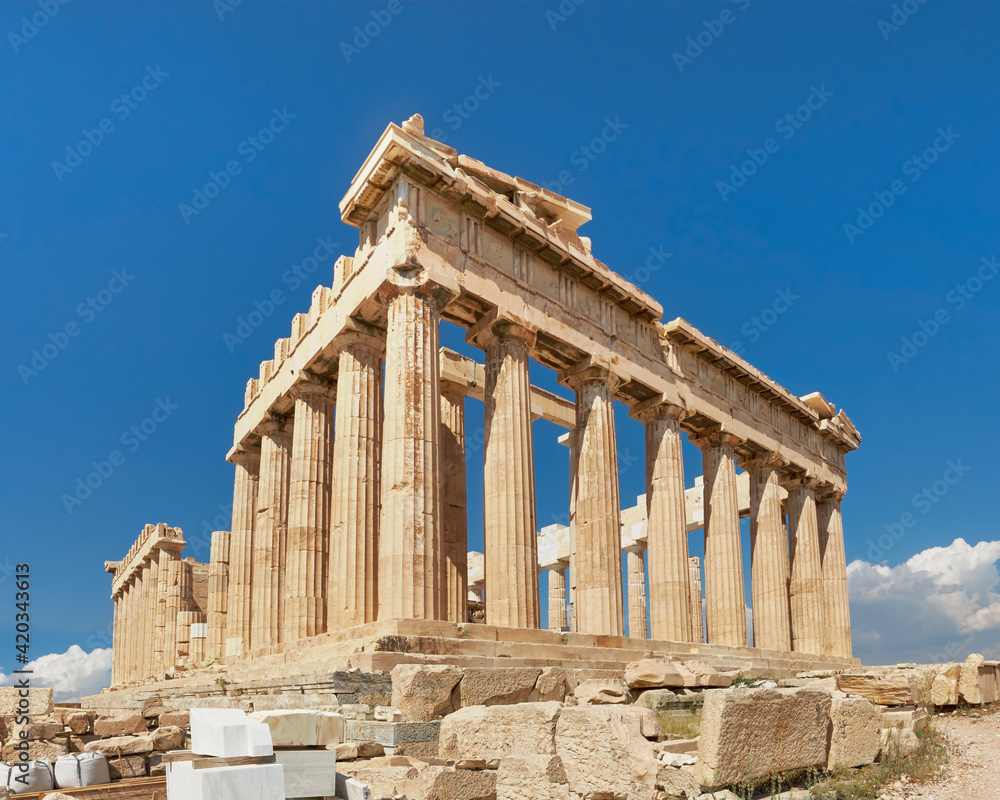 Acropolis, ancient Greek fortress in Athens, Greece. Panoramic image of Parthenon temple on a bright day with blue sky and faraway clouds. Classical Greek heritage