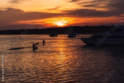 Beautiful sunset with the silhouette of people fishing on the shore