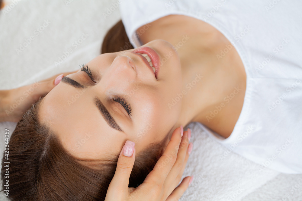Young pretty woman enjoying face massage procedure Young pretty woman enjoying face massage procedure