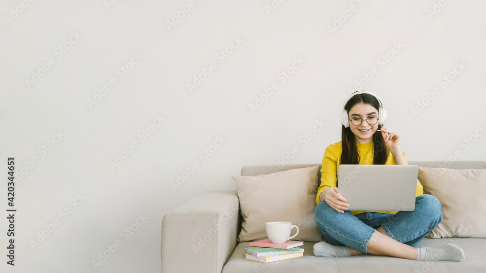Young attractive woman student study online with laptop, sitting on sofa at home. Distance learning and remote teaching concept with empty text place. Young attractive woman student study online with laptop, sitting on sofa at home. Distance learning and remote teaching concept with empty text place.