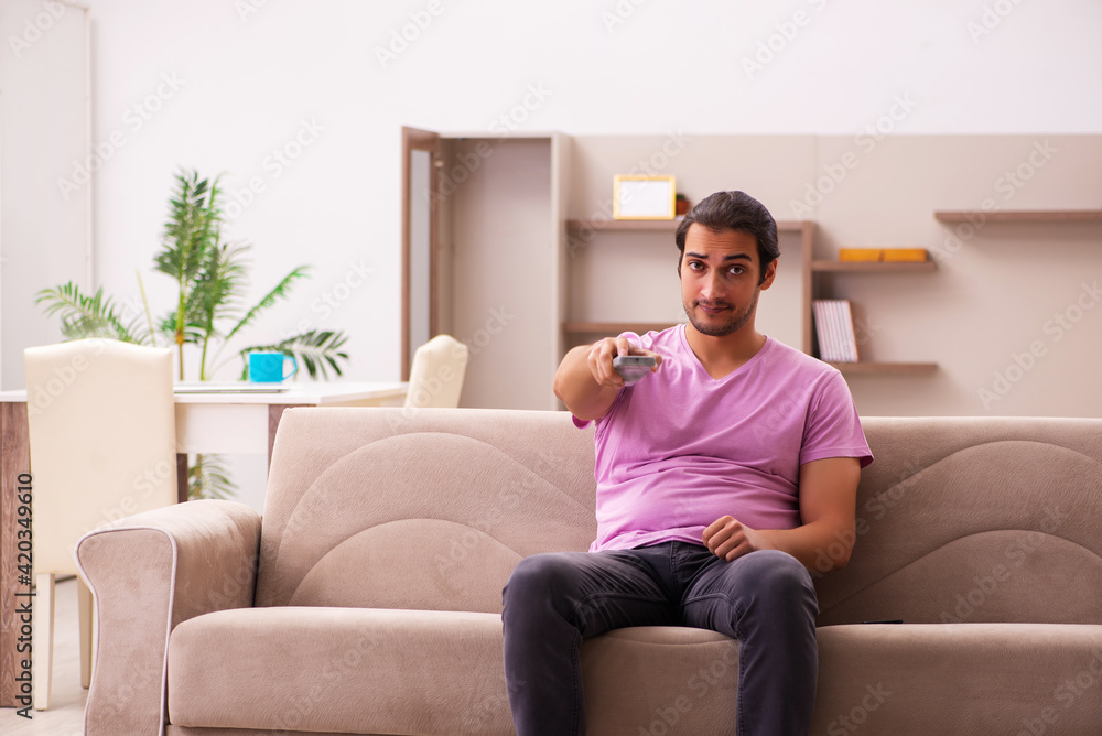 Young man watching tv at home during pandemic Young man watching tv at home during pandemic