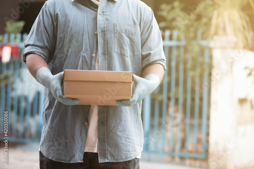 A businessman in a denim jacket wears blue protective gloves. With packages ordered online by customers to deliver to their doorstep. Fast service shipping concept © Treecha