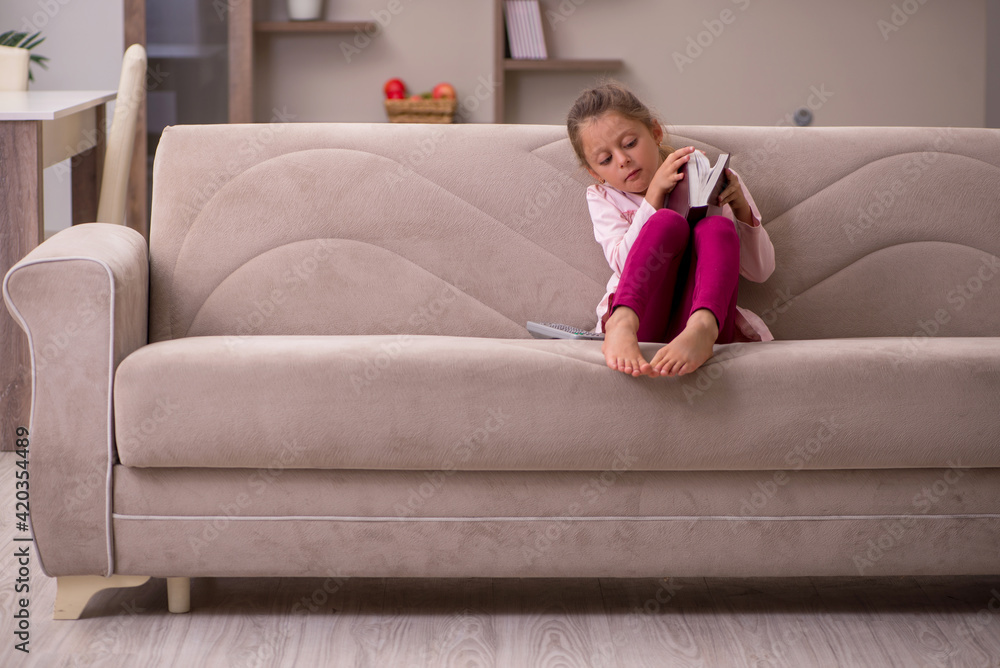 Small girl reading book at home
