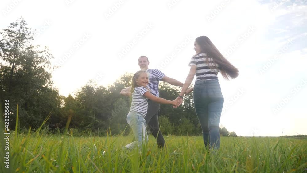 happy family mom dad and daughter play round dance. people in park kid dream concept. happy family parents with little kid child daughter play in the park on the grass holding hands lifestyle happy family mom dad and daughter play round dance. people in park kid dream concept. happy family parents with little kid child daughter play in the park on the grass holding hands lifestyle