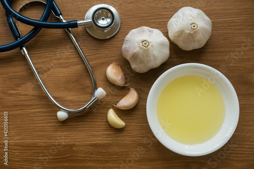 Top view of garlic ,garlic oil and stethoscope on wooden background.