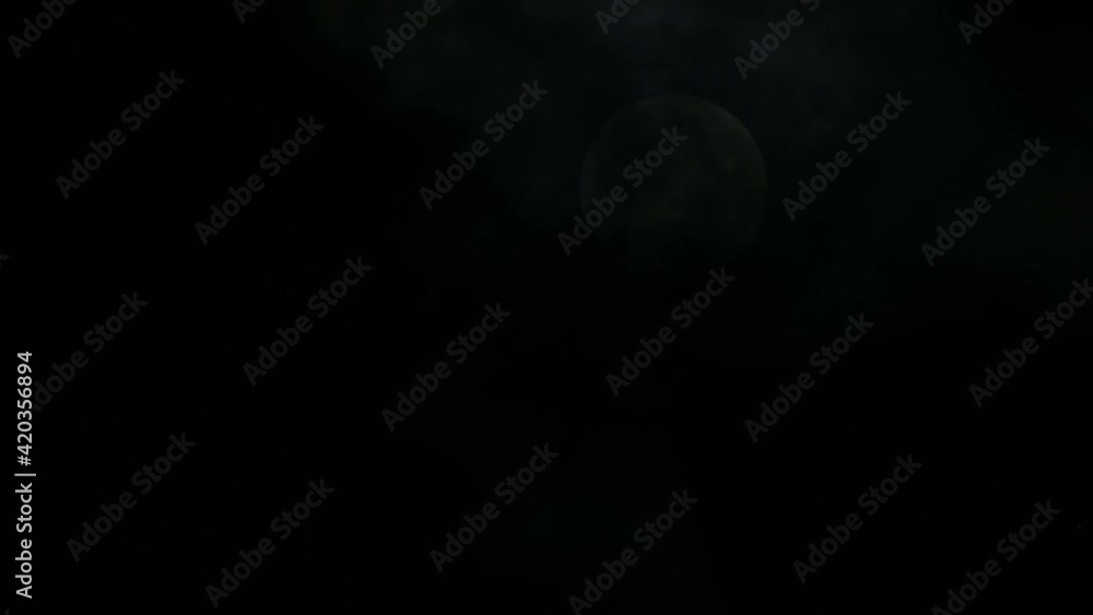 Moon almost seen behind the dark clouds in the middle of the night; slowly revealed as dark clouds move down the frame, one cold winter night at Kaeng Krachan National Park, Thailand. Moon almost seen behind the dark clouds in the middle of the night; slowly revealed as dark clouds move down the frame, one cold winter night at Kaeng Krachan National Park, Thailand.