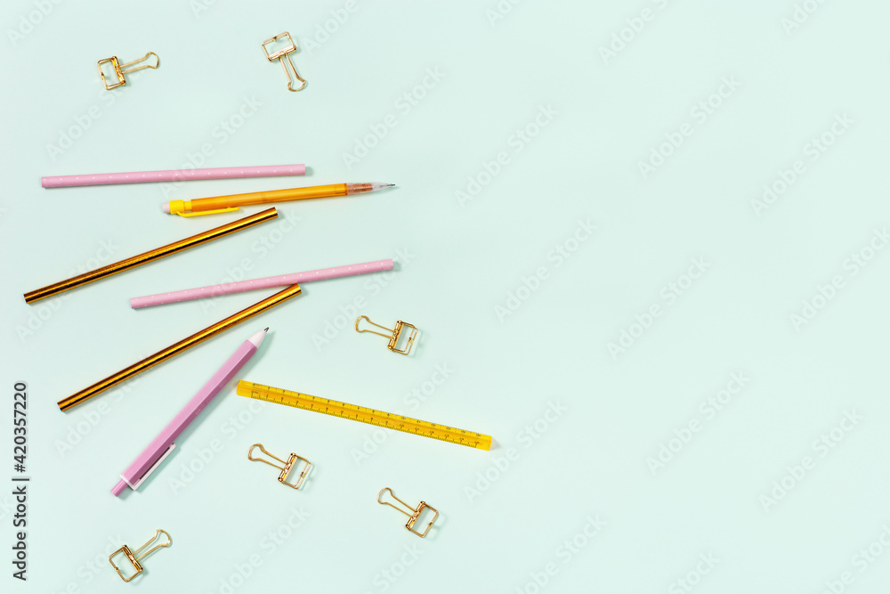 Flat lay with stationery for school or office. Pink and golden colored pencils, pens and metal paperclips. Flat lay with stationery for school or office. Pink and golden colored pencils, pens and metal paperclips.