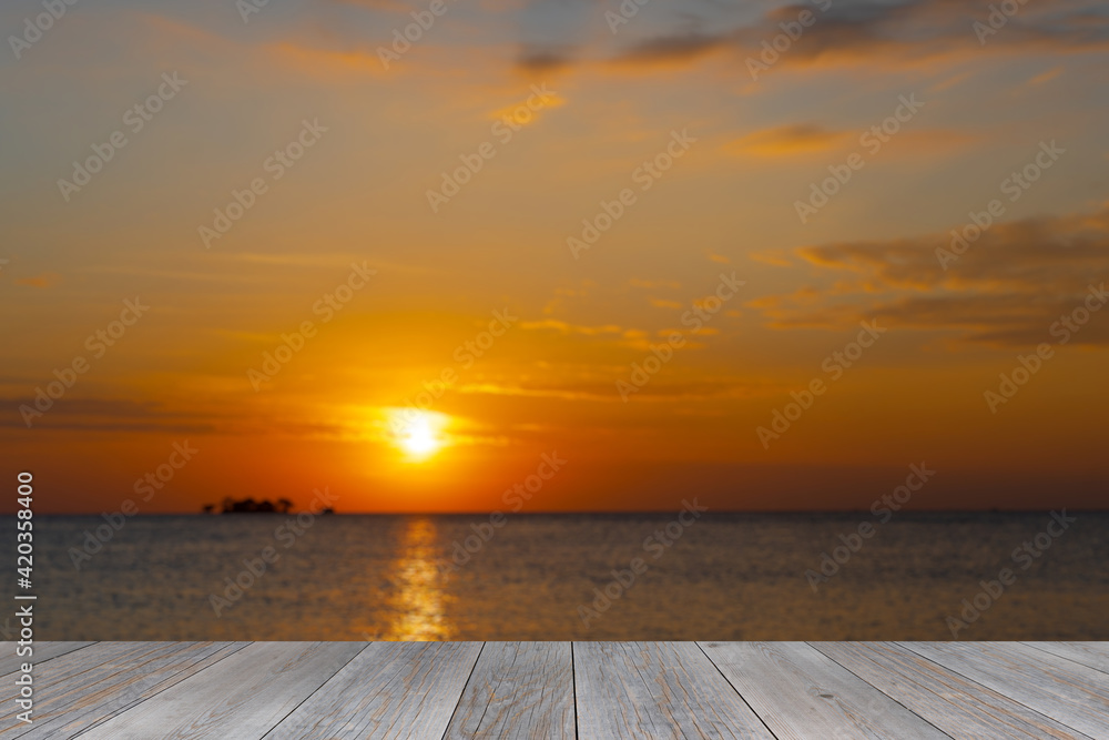 grey wooden aged terrace floor with blurred sunset at sea background