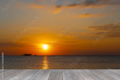 grey wooden aged terrace floor with blurred sunset at sea background © MasterSergeant