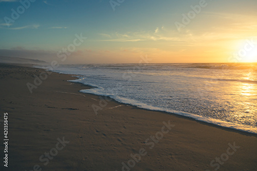 Beach sunset. Empty sand beach  sea waves  and sun setting down the horizon. Tranquil  calm scene  soft focus  copy space