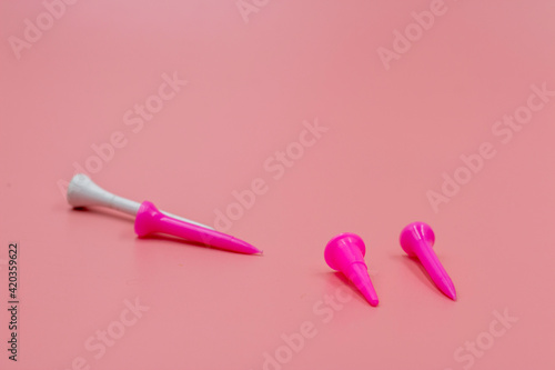 Pink golf tee on pink background