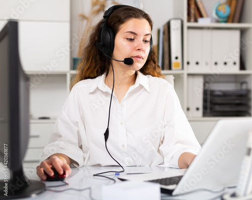 Portrait of friendly woman call center operator with headphones during work at her workplace
