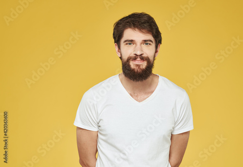 portrait of a man in a white t-shirt on a yellow background cropped view Copy Space
