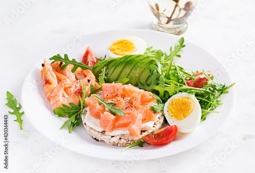 Ketogenic diet breakfast. Salt salmon salad with boiled shrimps, prawns, tomatoes, arugula, eggs and avocado. Keto, paleo lunch.